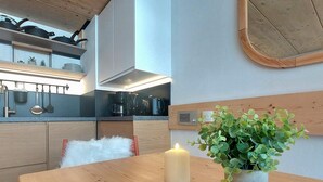 A modern kitchen with wooden cabinets, a round wooden table, a candle, and a potted plant. - Mezzanine Duplex 5 pers. · Ski-in/out · Mont Blanc View (Les Arcs 1800)