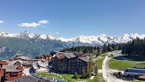 A mountainous landscape with snow-capped peaks, a ski resort with buildings, and a clear sky. - Mezzanine Duplex 5 pers. · Ski-in/out · Mont Blanc View (Les Arcs 1800)