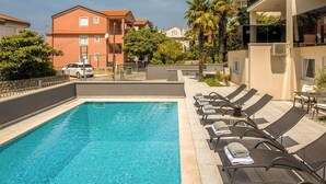 A swimming pool with lounge chairs and a clear blue sky.