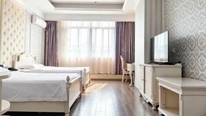 Habitación de hotel con dos camas, un escritorio, una silla, un televisor y una ventana con cortinas.