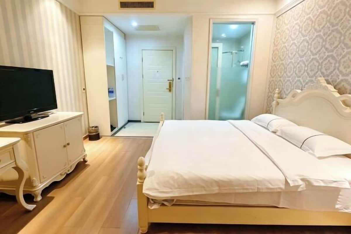 A bedroom with a bed, a television, and a dresser.