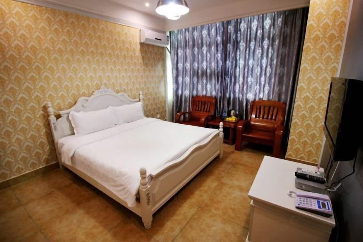 A hotel room with a bed, a desk with a telephone, and a television.
