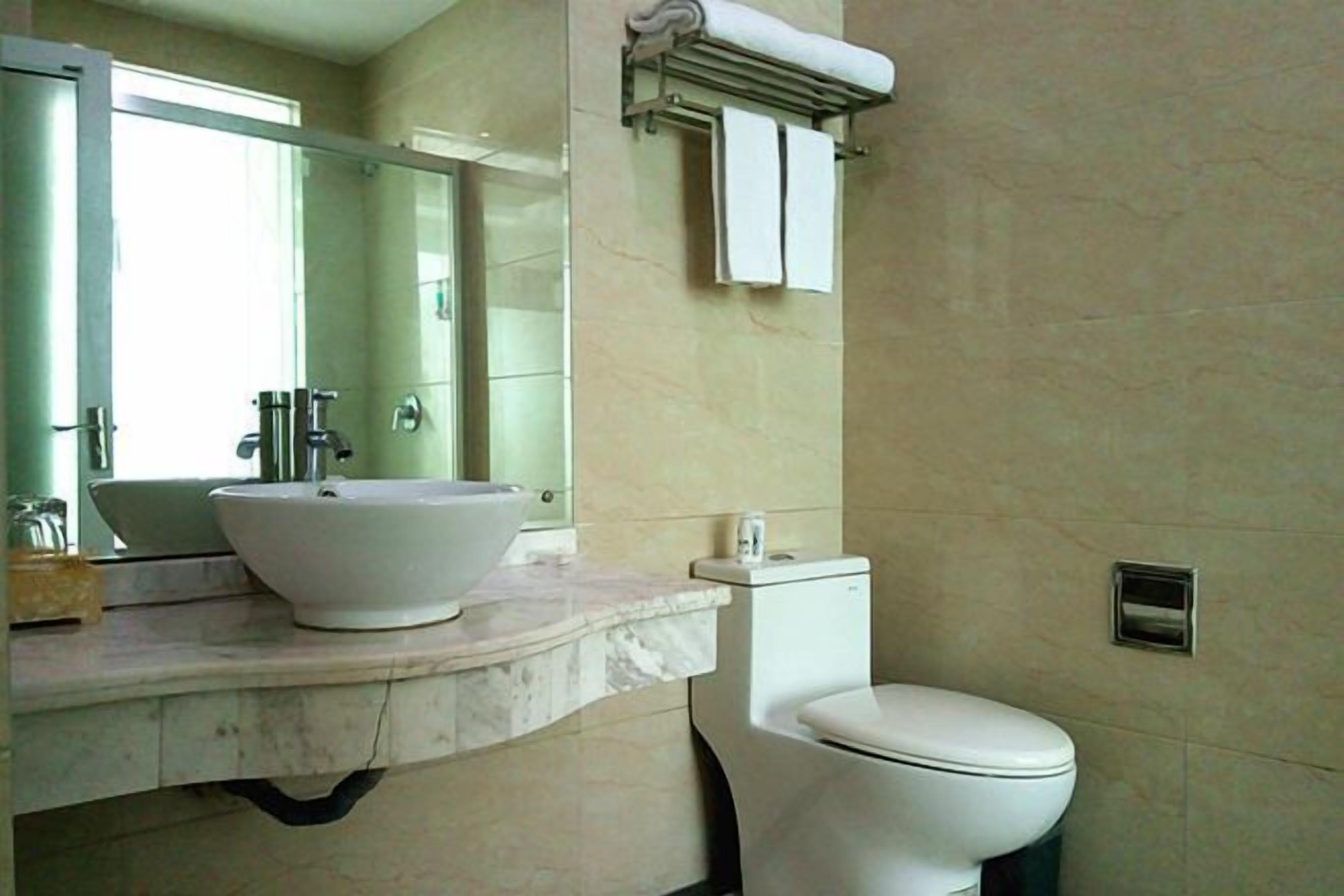 A bathroom with a marble sink, a toilet, and a towel rack.