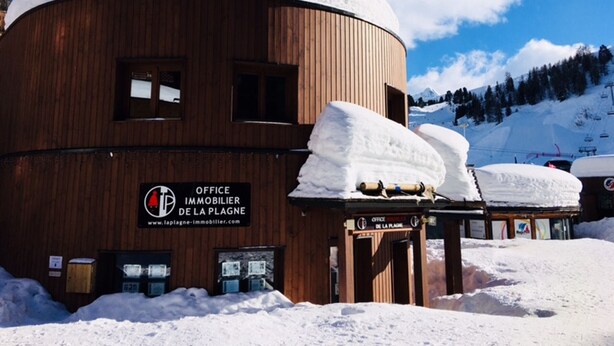 Un edificio de madera con un letrero que dice 'Office Immobilier de la Plagne'.