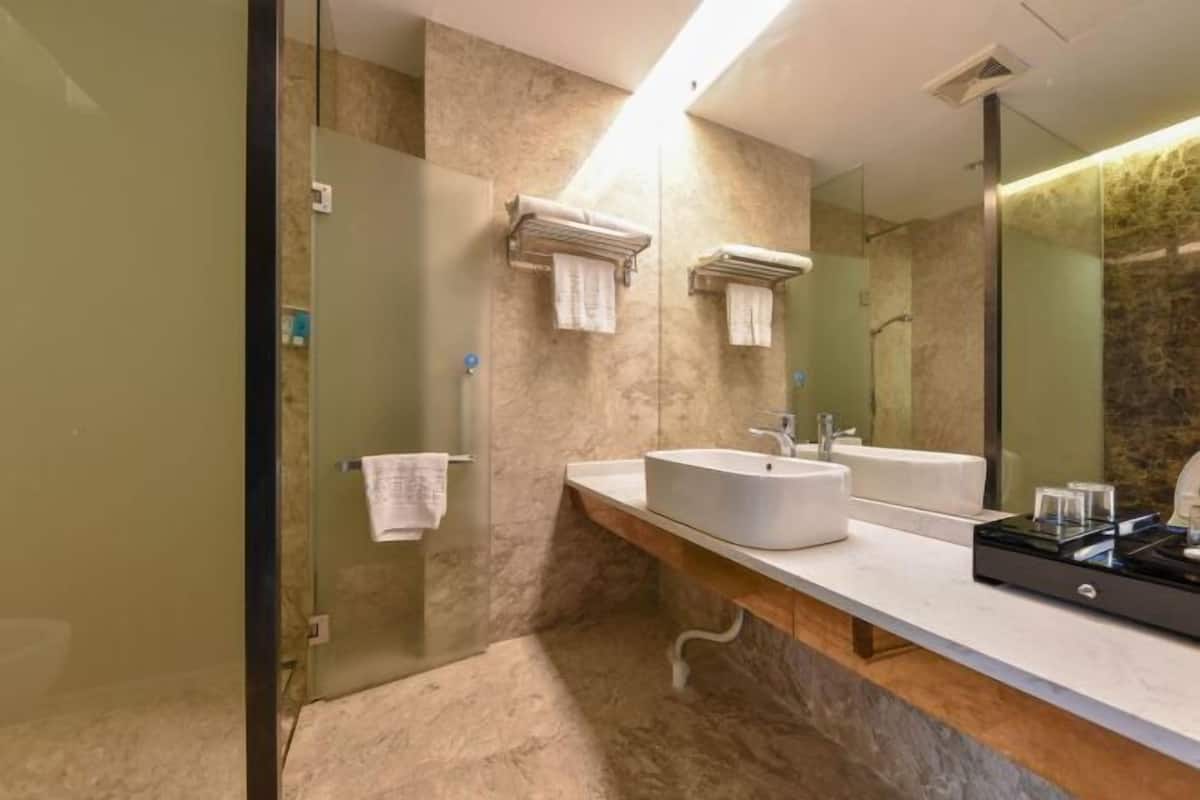A modern bathroom with a glass shower enclosure, a marble countertop, a sink, and a large mirror.