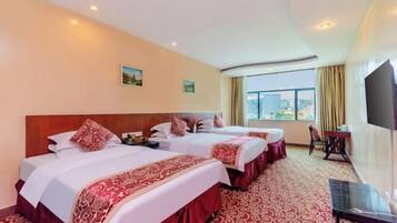 Habitación de hotel con dos camas, televisión, escritorio y vistas a la ciudad.