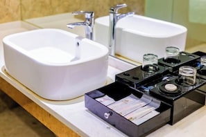 Une salle de bain avec deux lavabos blancs, un miroir et un distributeur de savon noir contenant une bouteille de savon.