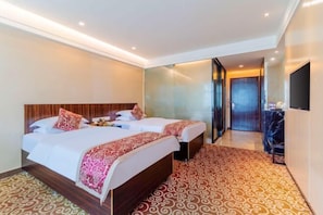 Une chambre d’hôtel avec deux lits, un grand miroir, un téléviseur à écran plat et une moquette à motifs.