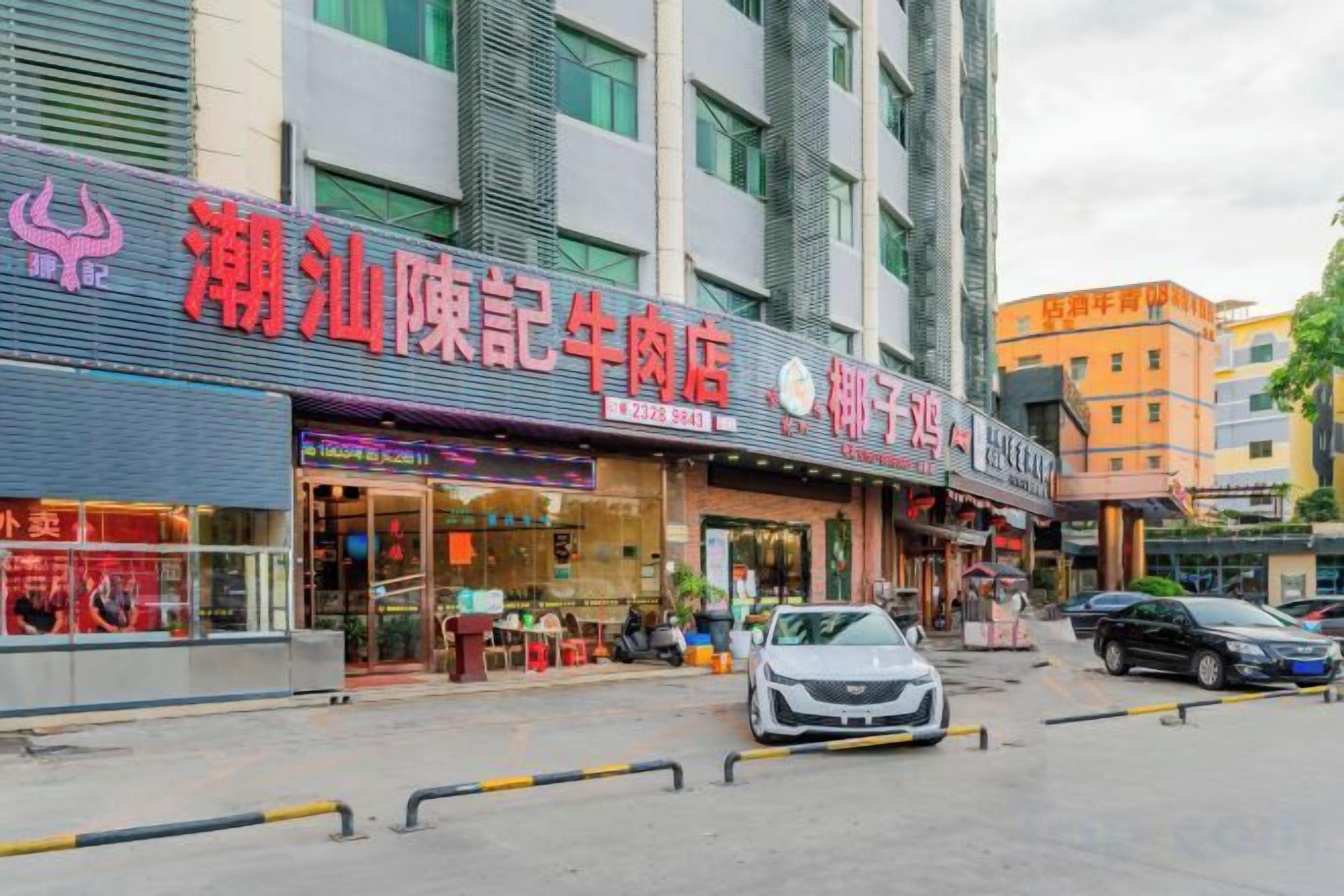 Um edifício comercial com várias fachadas, incluindo um restaurante e uma loja com uma placa vermelha chamativa.