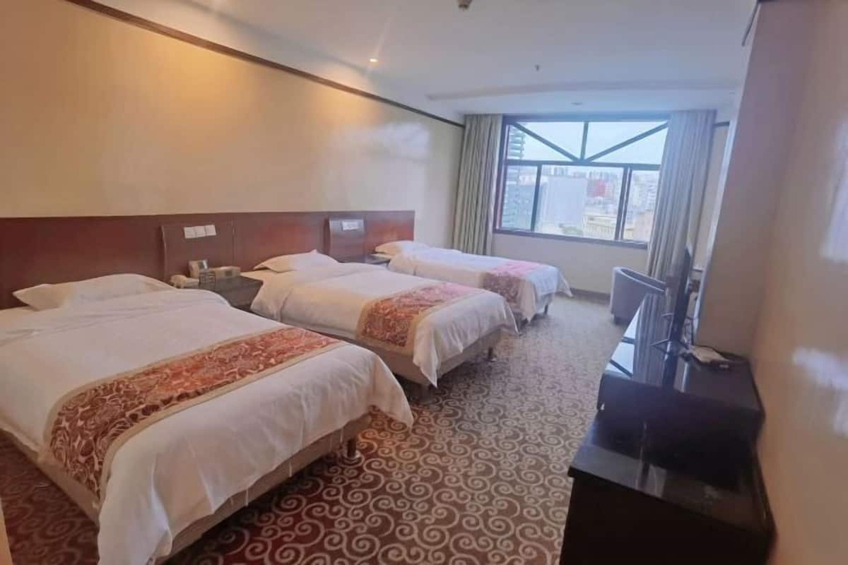A hotel room with two beds, a TV, and a large window.