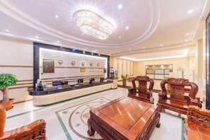 Un hall d’hôtel comprenant un comptoir d’accueil, un espace salon et un lustre.