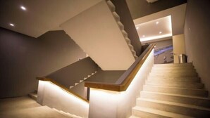 A modern staircase with a wooden handrail and a lighted landing area. - Happy Air Hotel (Jiande) (Jiande)