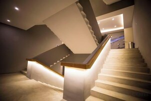 Una escalera con barandilla de madera y un rellano iluminado.