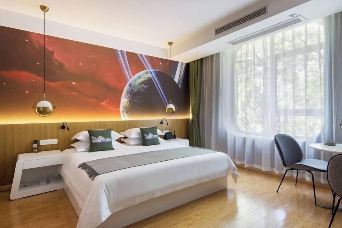 A hotel room with a large bed, a desk, and a view of the outdoors.