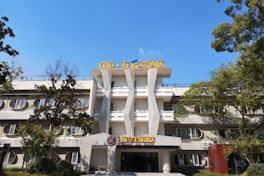 A building with a central entrance, multiple windows, and a sign above the entrance. - Happy Air Hotel (Jiande) (Jiande)