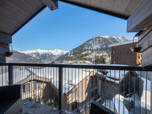Enjoy breathtaking views of snow-capped peaks and a serene valley from this mountain retreat's balcony.