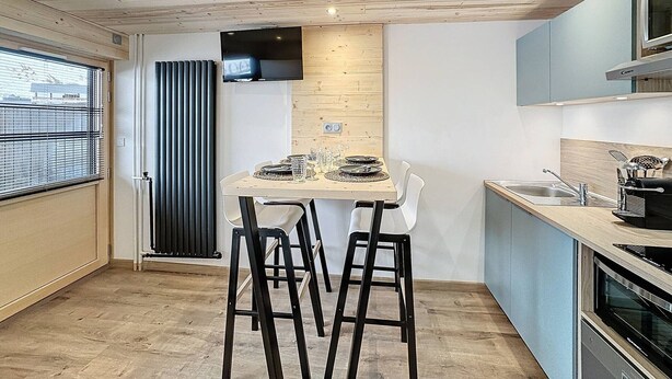 A modern kitchen with a wooden ceiling, a dining table with chairs, a built-in oven, and a window with blinds. - Renovated studio for 4 at slopeside - La Croisette (Les Belleville)