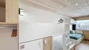 A compact room with a bunk bed, wooden ceiling, and a window with a city view. - Renovated studio for 4 at slopeside - La Croisette (Les Belleville)