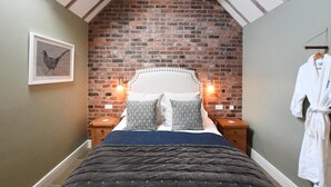 A bedroom with a brick wall, a bed with patterned pillows, and a framed picture on the wall. - Boutique Farm stay cottage in Worcestershire - Hot Tub / Dog Friendly (worcester)