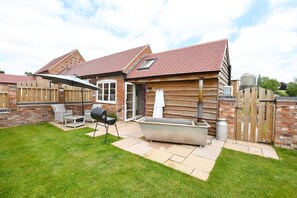 A house with a brick exterior, a tiled roof, and a fenced backyard.