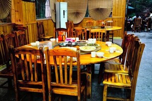 A wooden dining table with chairs, a kettle, and dishes. - Nongfu Hostel (Rongshui)
