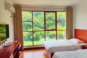 A hotel room with a large window, two beds, a TV, and a desk. - Nongfu Hostel (Rongshui)