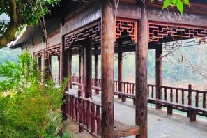 A traditional wooden pavilion with a stone floor, surrounded by a wooden railing. - Nongfu Hostel (Rongshui)