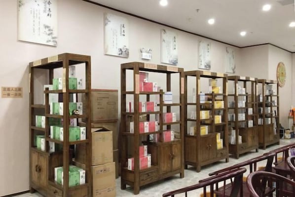 A row of wooden bookshelves filled with various boxes, likely containing products or books, in a room with a simple, clean design and traditional Asian wall art. - Bo Yuan Mei Yu Hotel (Zhuhai)