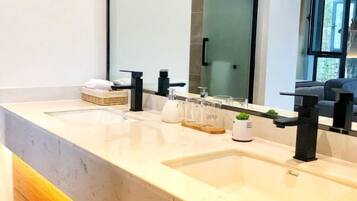 A modern bathroom with two sinks, a large mirror, and a window.