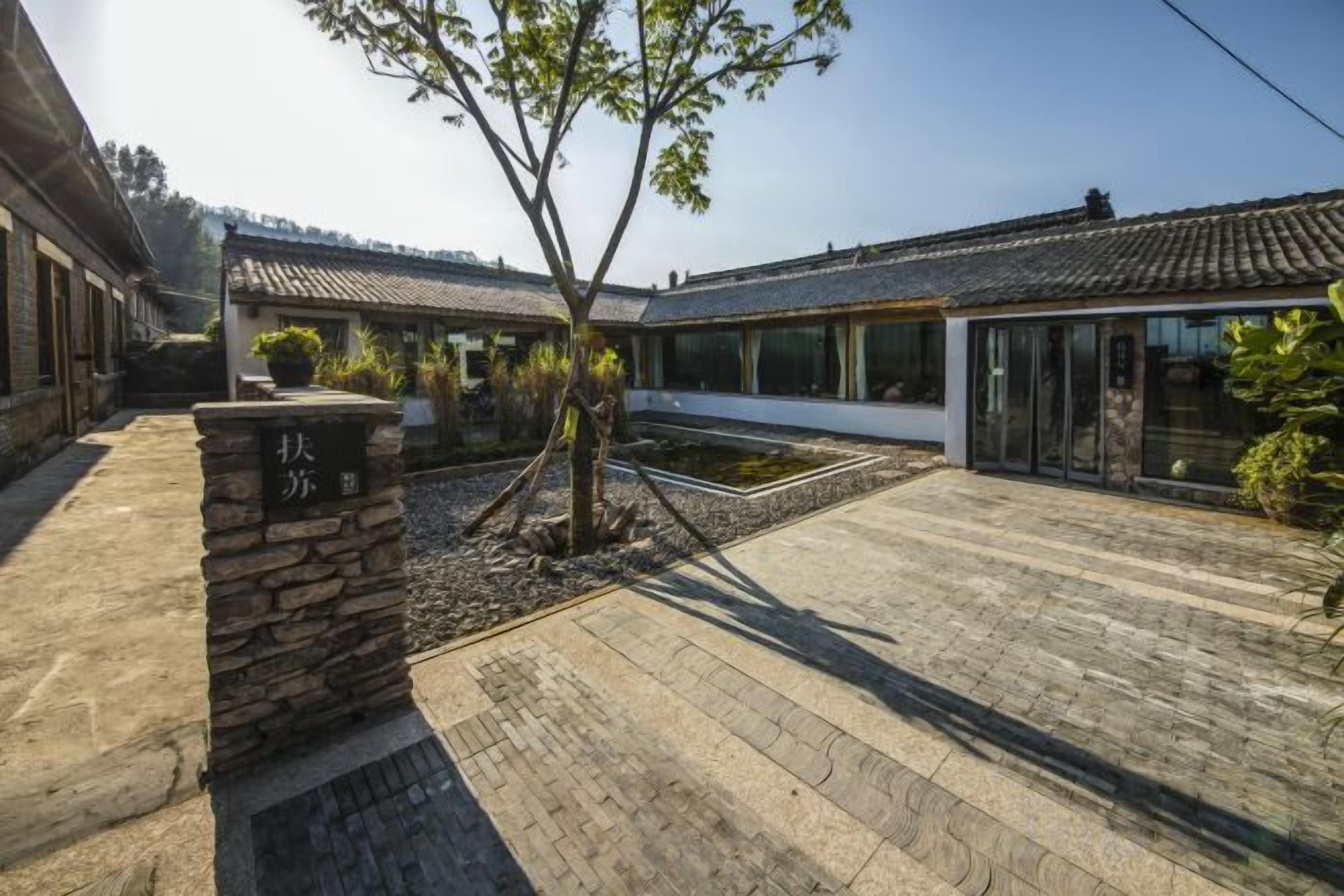 A courtyard with traditional architecture, stone pathways, and a small tree.