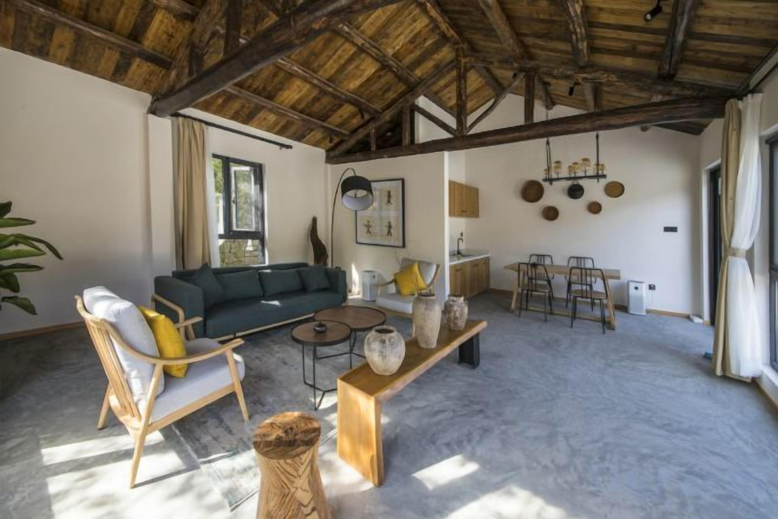 A spacious living area with a high ceiling, a sofa, chairs, a coffee table, and a dining table.