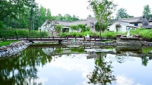 Um lago tranquilo com pontes de pedra, cercado por vegetação exuberante e edifícios tradicionais.
