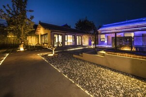 Una casa moderna con entrada pavimentada, zona de grava e iluminación exterior.