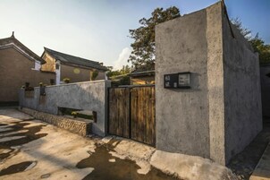 Un edificio de concreto con un portón de madera, un banco pequeño y un letrero en la pared.