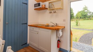 Cocina compacta con puerta azul, techo de madera y vista a un jardín a través de un ventanal.