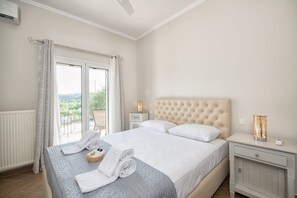 A bedroom with a large bed, a nightstand, a bedside table, and a view of the outdoors.