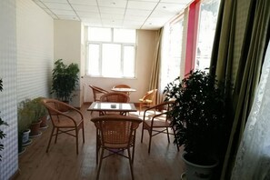 Una habitación con una mesa de comedor, sillas, plantas en macetas y un ventanal grande.