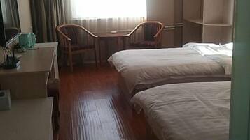 Una habitación de hotel con dos camas, un escritorio con silla y una ventana con cortinas.