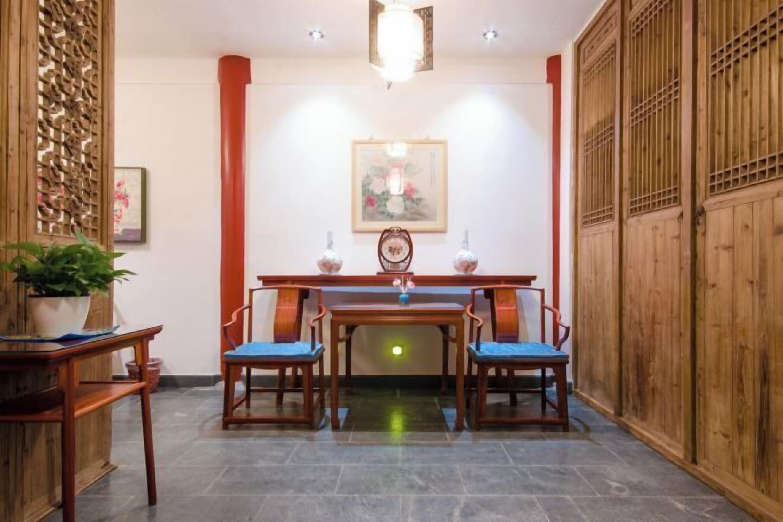 A traditional dining area with a wooden table and chairs, a decorative screen, and a framed artwork on the wall.