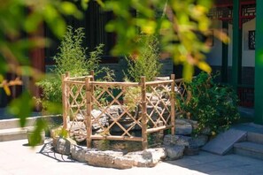 Una estructura de madera tradicional con plantas, rodeada de rocas y escalones.