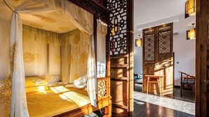 Una habitación tradicional con cama, un separador de madera y vistas al exterior.