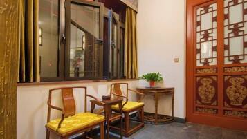 A traditional room with a wooden door, a window with a curtain, and a small table with a plant.