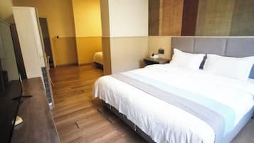 Une chambre d’hôtel avec un grand lit, un plancher en bois, un bureau et une table de chevet avec une lampe.