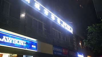 A building with illuminated signage, including a prominent blue sign with white text and a red sign with white text.
