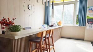 A modern hotel room with a wooden bar area, a clock on the wall, and a window with curtains. - Aishang City Inn (Chongqing)