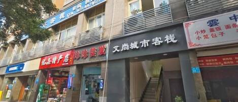 A row of storefronts with signage, including a black sign with white text, a red sign with white text, and a blue sign with white text.