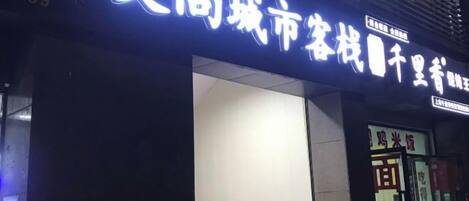 A building with illuminated signage, a visible entrance, and a storefront with glass doors.