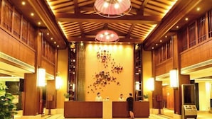Un vestíbulo de hotel con paneles de madera, un mostrador de recepción y una pared decorativa con diseños circulares.