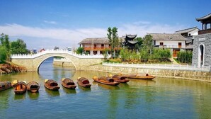 Un puente tradicional cruza un río tranquilo, rodeado de edificios tradicionales con estilos arquitectónicos diferentes.