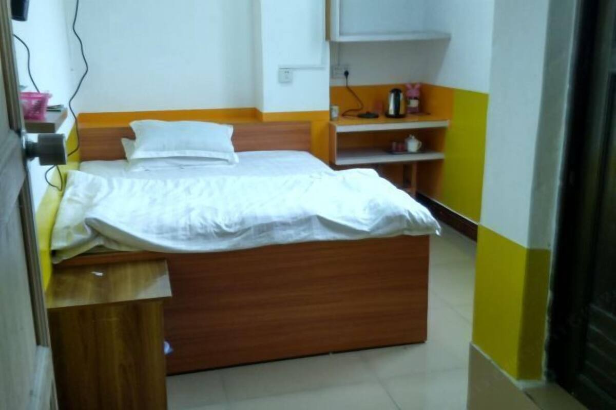 Una cama individual con cabecera de madera en una habitación con decoración amarilla y blanca.